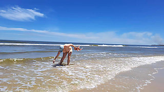 Amateur filming. A nudist plays with waves on the ocean shore.